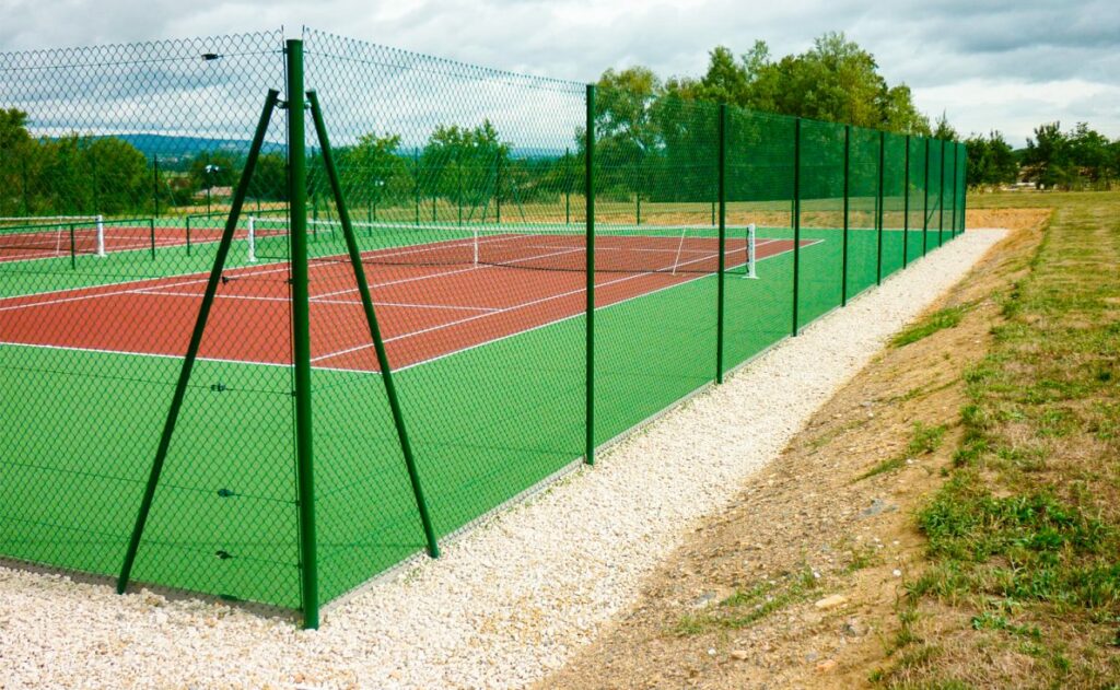 Un Court De Tennis Avec Une Clôture Verte Et Des Arbres En Arrière